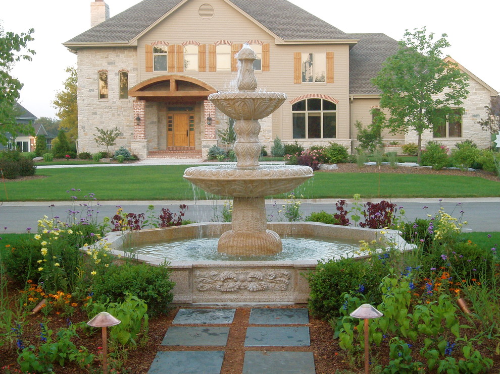 This is an example of an expansive mediterranean front full sun garden in Milwaukee with a water feature and natural stone paving.