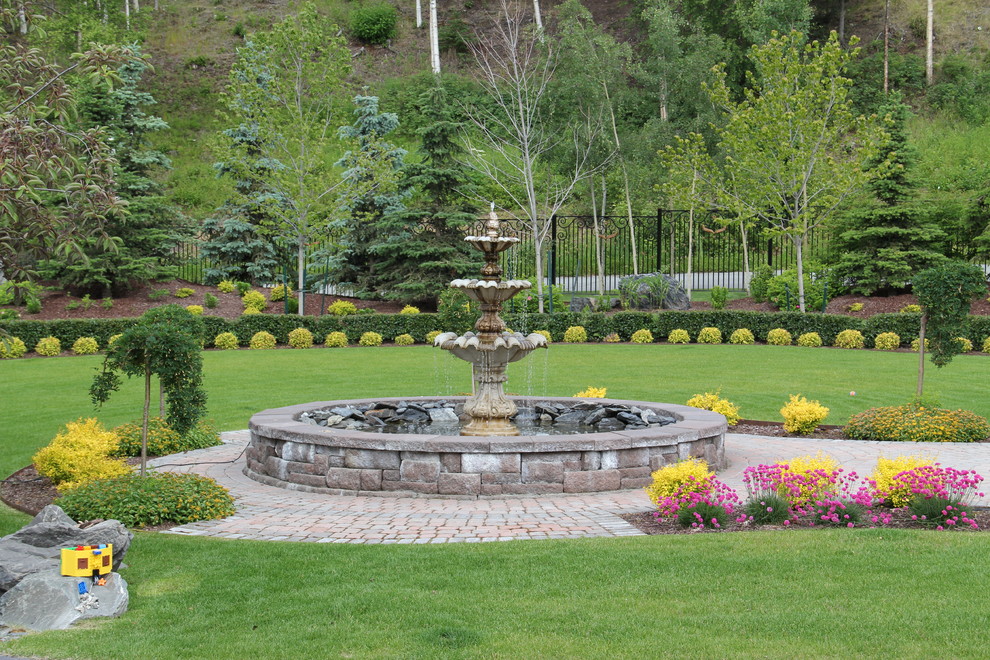 Exempel på en mycket stor klassisk trädgård i full sol framför huset, med en fontän och marksten i tegel