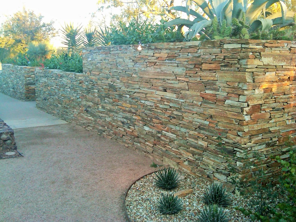 Immagine di un ampio giardino moderno esposto a mezz'ombra davanti casa in estate con un muro di contenimento e pavimentazioni in pietra naturale