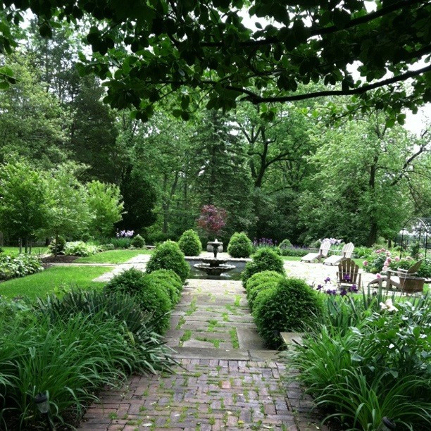 Diseño de jardín tradicional grande en patio trasero con jardín francés, exposición parcial al sol y adoquines de piedra natural