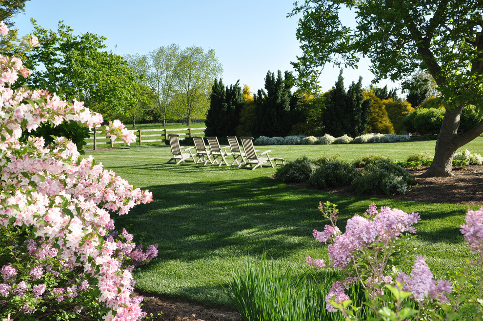 Immagine di un ampio giardino formale tradizionale esposto in pieno sole dietro casa in estate con pacciame