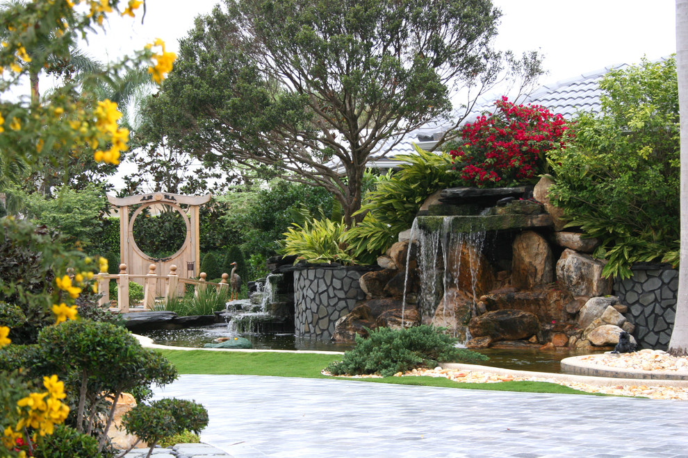 Foto på en stor orientalisk bakgård i full sol, med en fontän och naturstensplattor