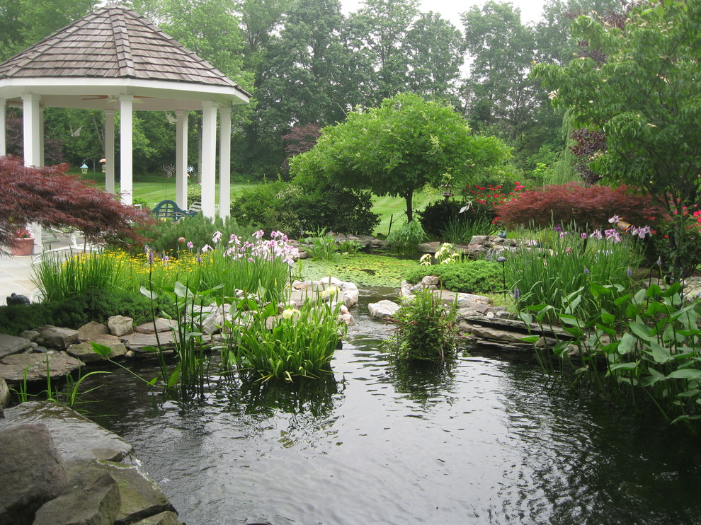 Design ideas for a medium sized classic back formal partial sun garden for spring in DC Metro with a pond and natural stone paving.