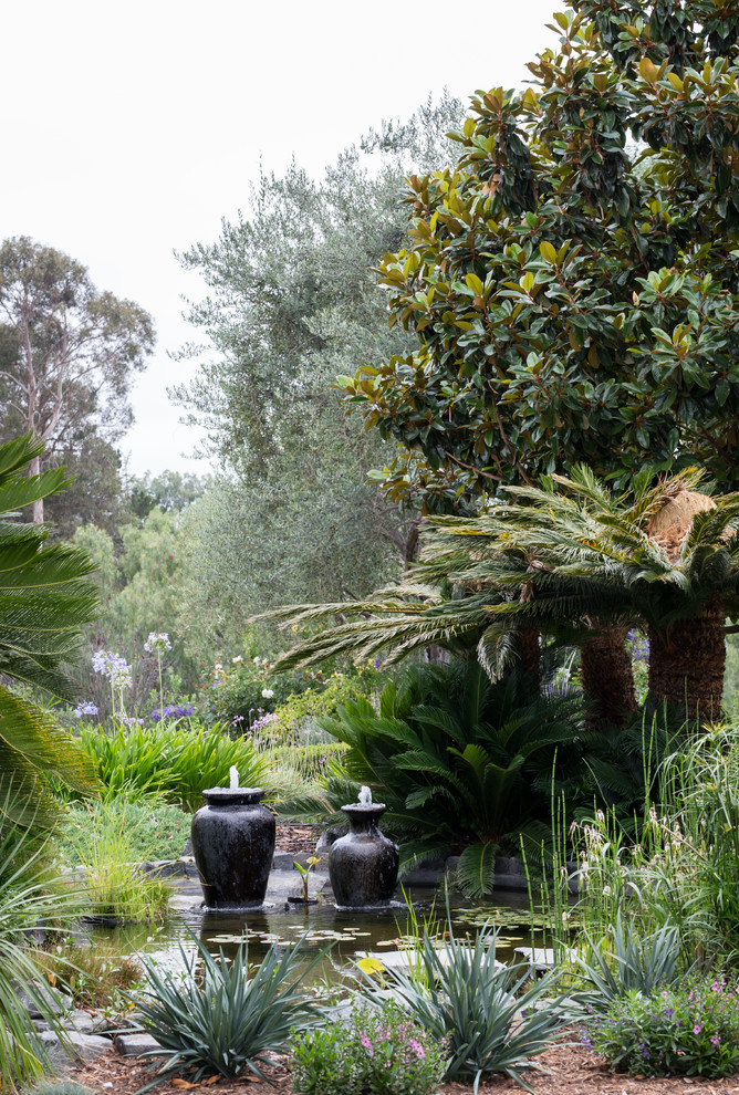 Idéer för mycket stora tropiska formella trädgårdar i full sol framför huset, med en fontän