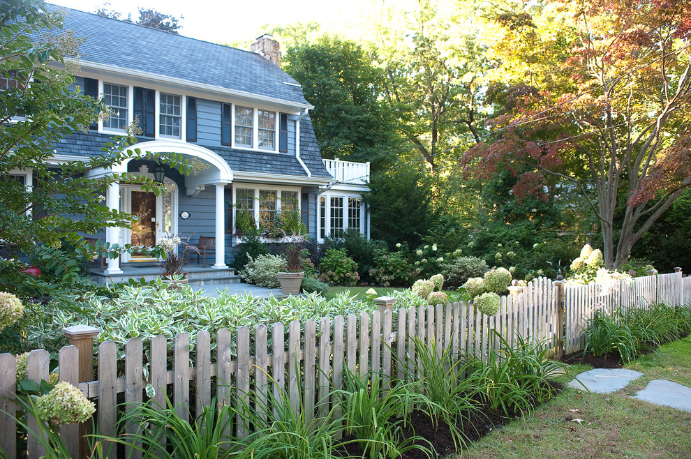 Exempel på en klassisk trädgård i skuggan framför huset, med naturstensplattor