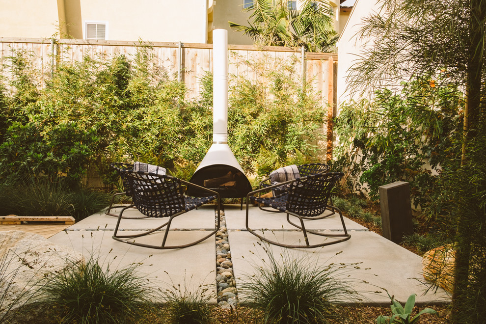 Immagine di un piccolo patio o portico tropicale dietro casa con un focolare, pavimentazioni in cemento e nessuna copertura
