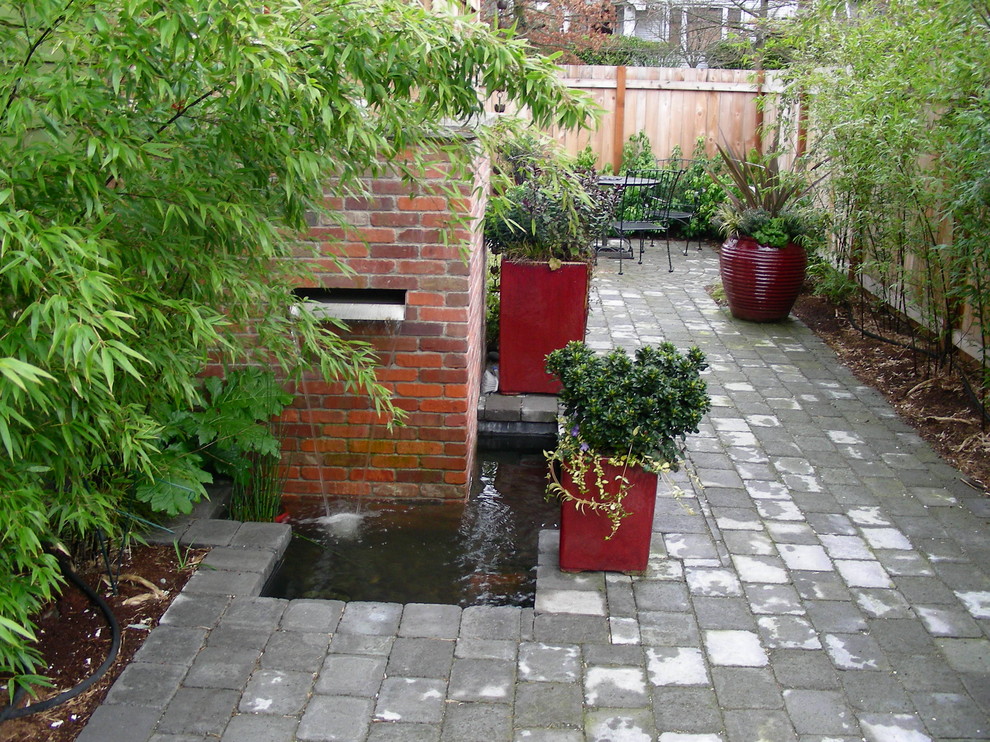 Exempel på en mellanstor modern bakgård, med en fontän och naturstensplattor