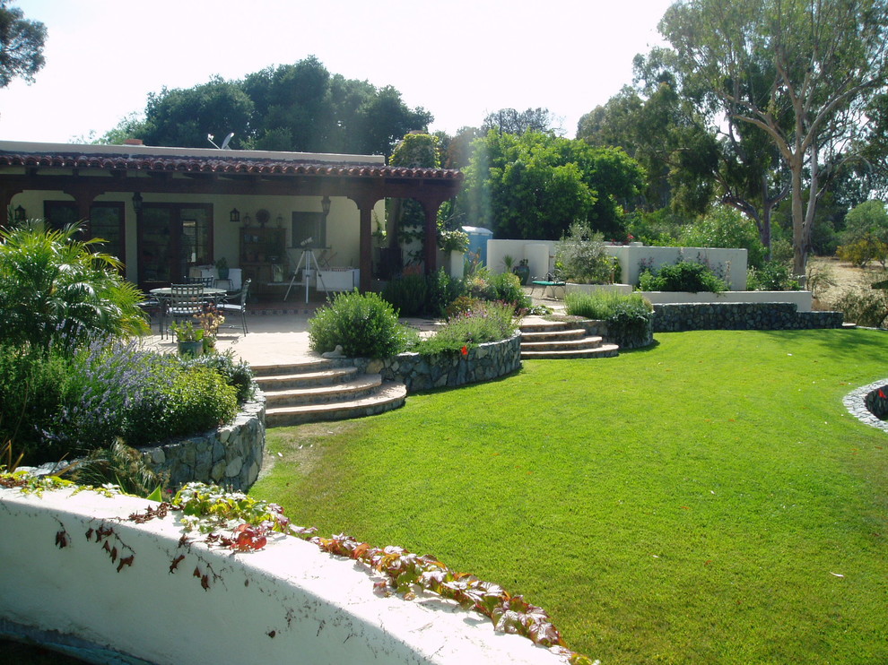 Inspiration pour un jardin arrière méditerranéen avec une cheminée, une exposition ensoleillée et des pavés en pierre naturelle.