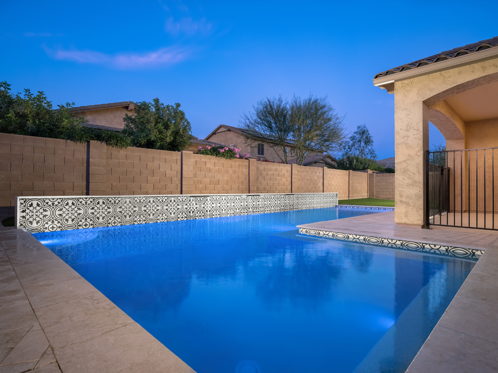 Example of a large transitional backyard pool fountain design in Phoenix with decking
