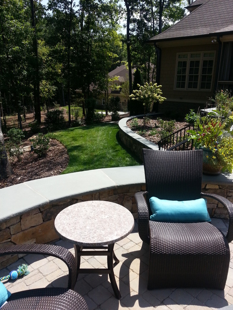 Photo of a large traditional partial sun backyard stone retaining wall landscape in Raleigh.