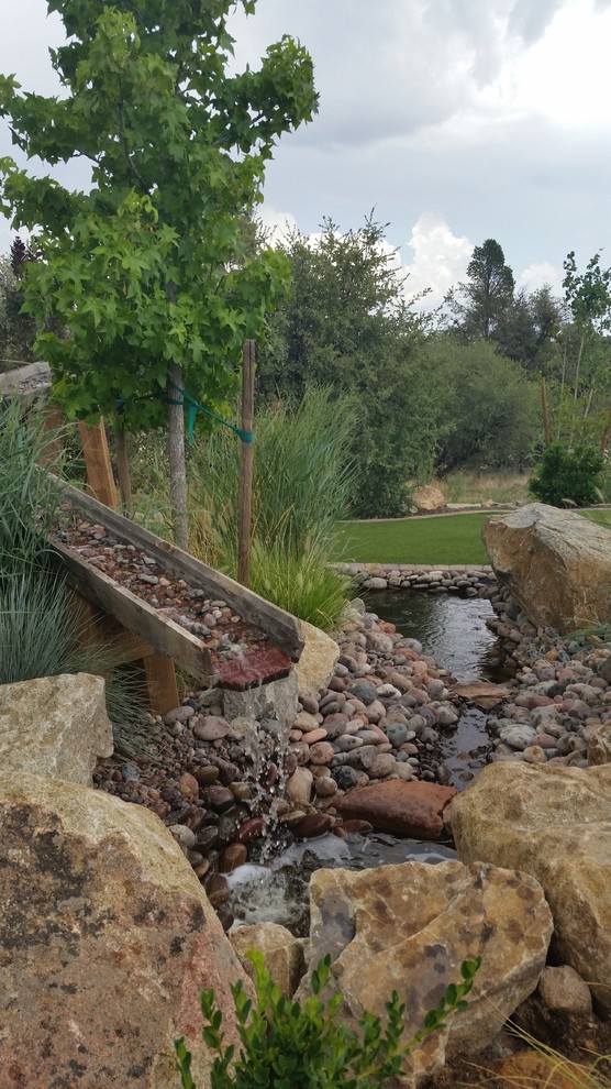 This is an example of a large rustic back partial sun garden for spring in Phoenix with a water feature and gravel.