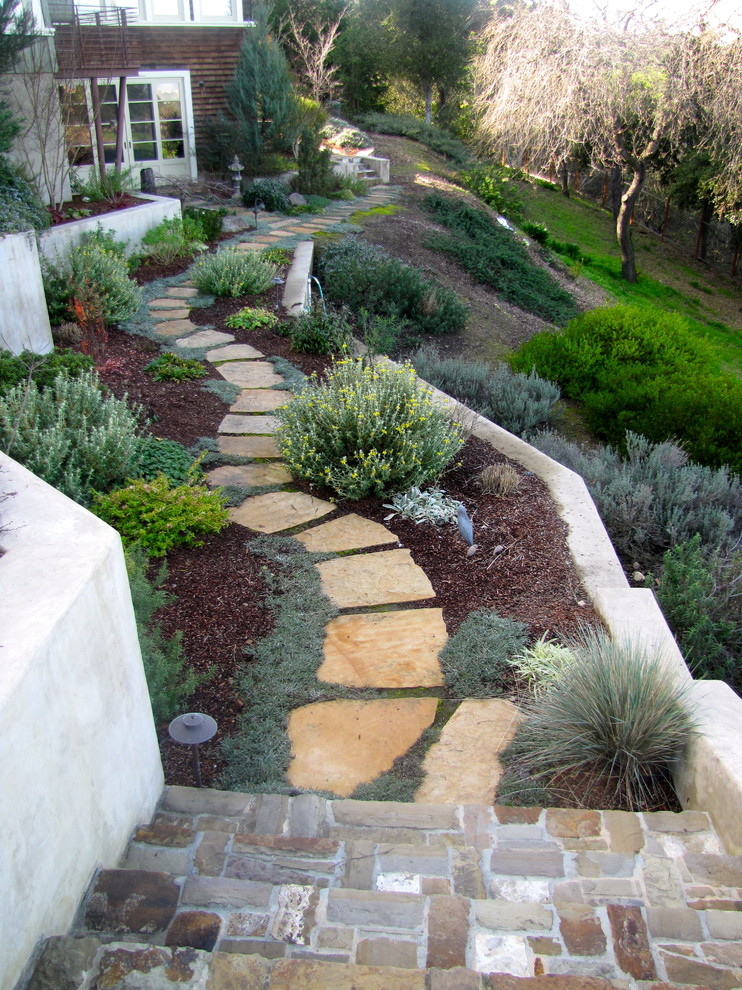 Ejemplo de jardín clásico en ladera con adoquines de piedra natural