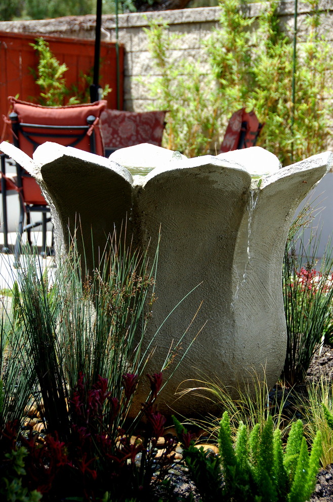 Photo of a medium sized world-inspired back full sun garden in Orange County with a water feature and concrete paving.