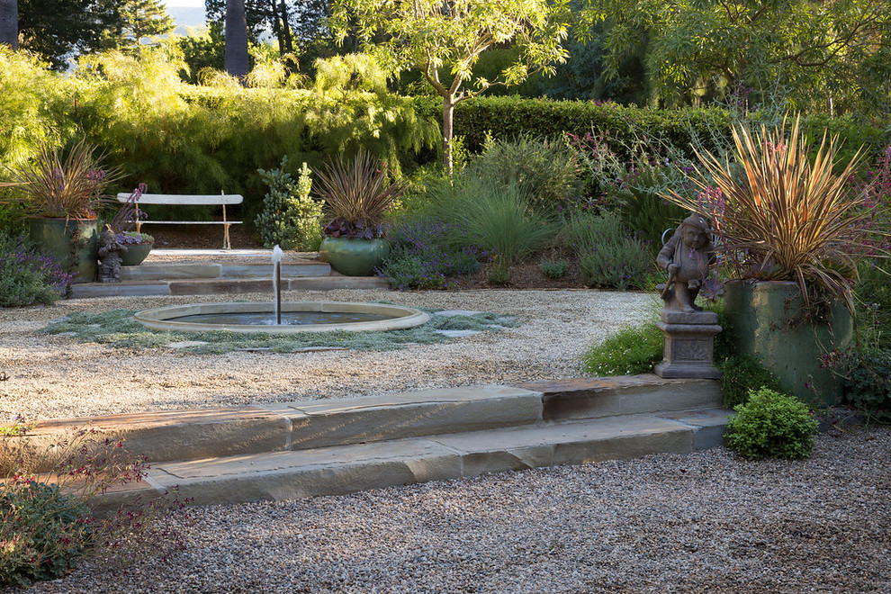 Diseño de jardín campestre grande en patio delantero con jardín francés, fuente, exposición total al sol y gravilla