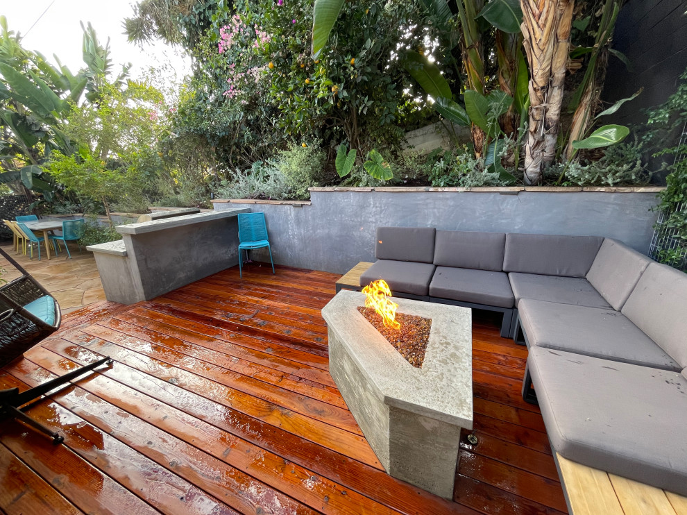 Kleiner, Halbschattiger Moderner Garten im Frühling, hinter dem Haus mit Feuerstelle, Natursteinplatten und Steinzaun in Los Angeles