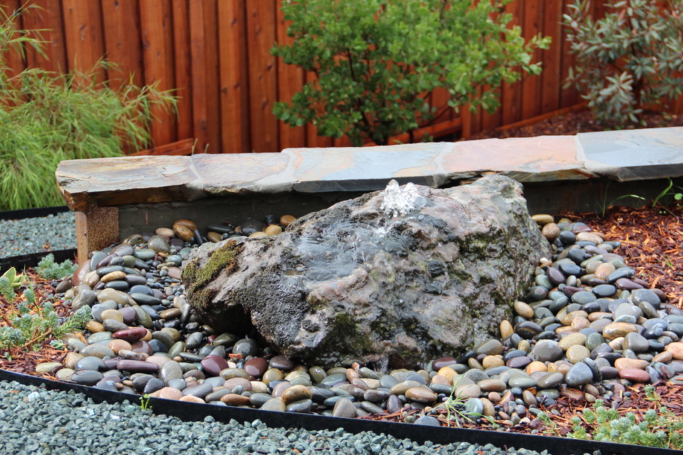 This is an example of a medium sized mediterranean back formal partial sun garden in San Luis Obispo with a water feature and gravel.