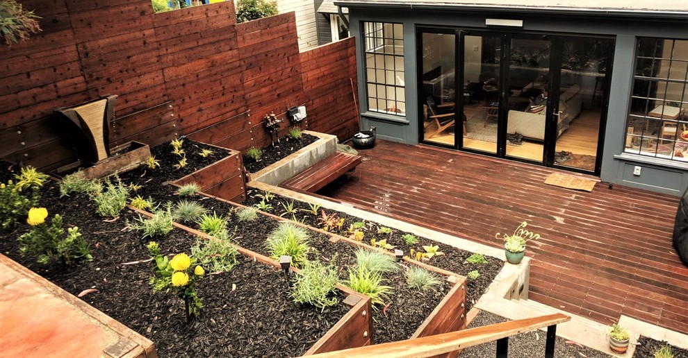 Идея дизайна: солнечный засухоустойчивый сад среднего размера на заднем дворе в средиземноморском стиле с подпорной стенкой, хорошей освещенностью, мульчированием и с деревянным забором
