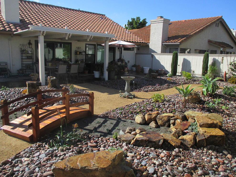 На фото: большой солнечный засухоустойчивый сад на заднем дворе в стиле фьюжн с хорошей освещенностью и покрытием из гравия