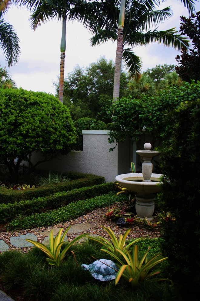 Cette image montre un jardin avant ethnique avec un point d'eau, une exposition partiellement ombragée et des pavés en pierre naturelle.
