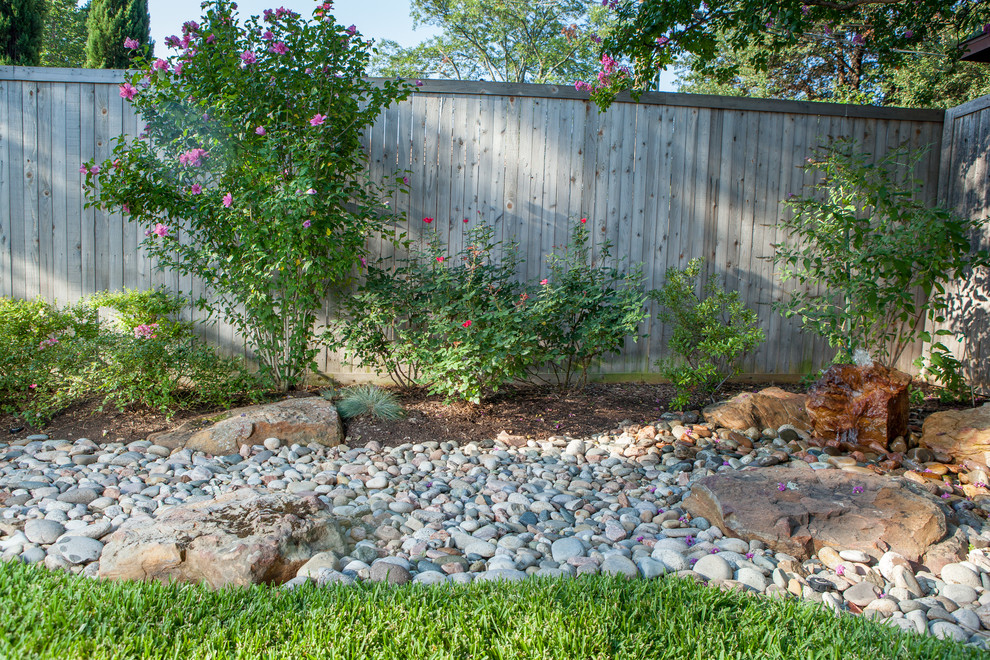 Aménagement d'un petit jardin arrière classique l'été avec un point d'eau, une exposition partiellement ombragée et des pavés en pierre naturelle.