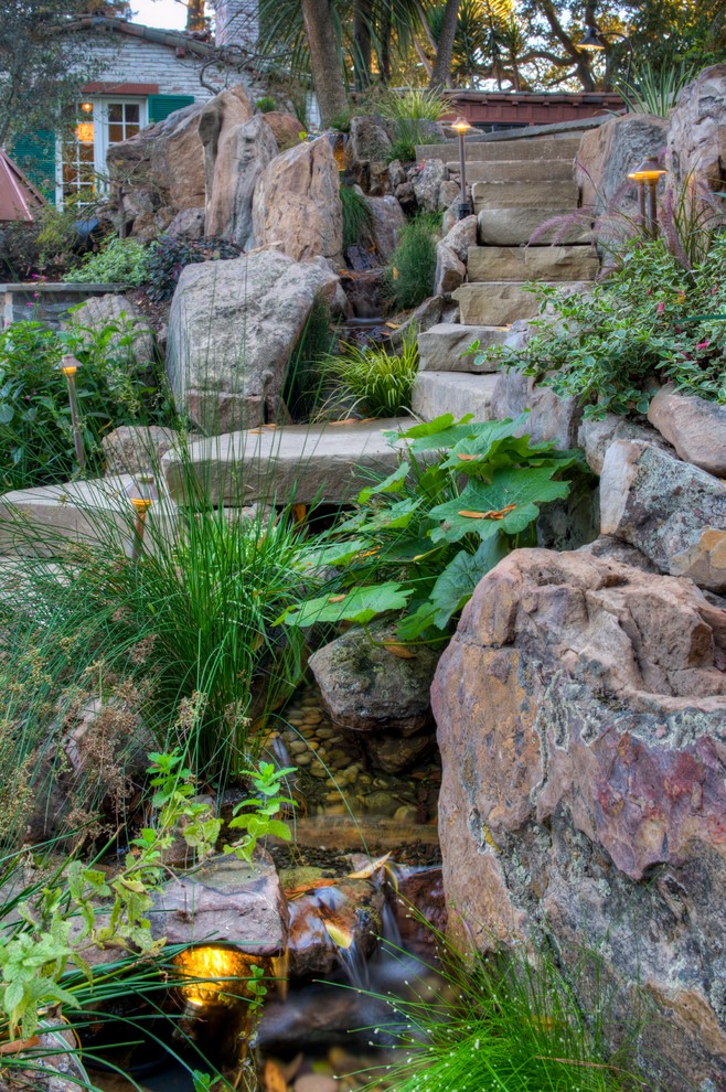 Ejemplo de jardín clásico renovado en ladera con fuente y adoquines de piedra natural