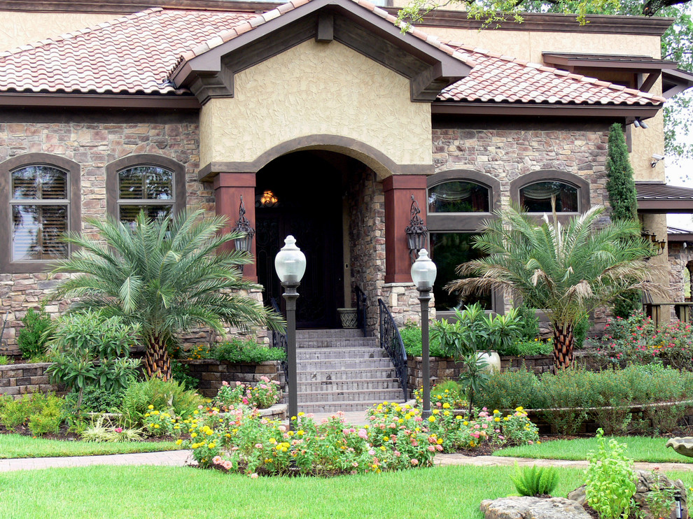 Photo of an expansive traditional front full sun garden for summer in Houston with a garden path and natural stone paving.