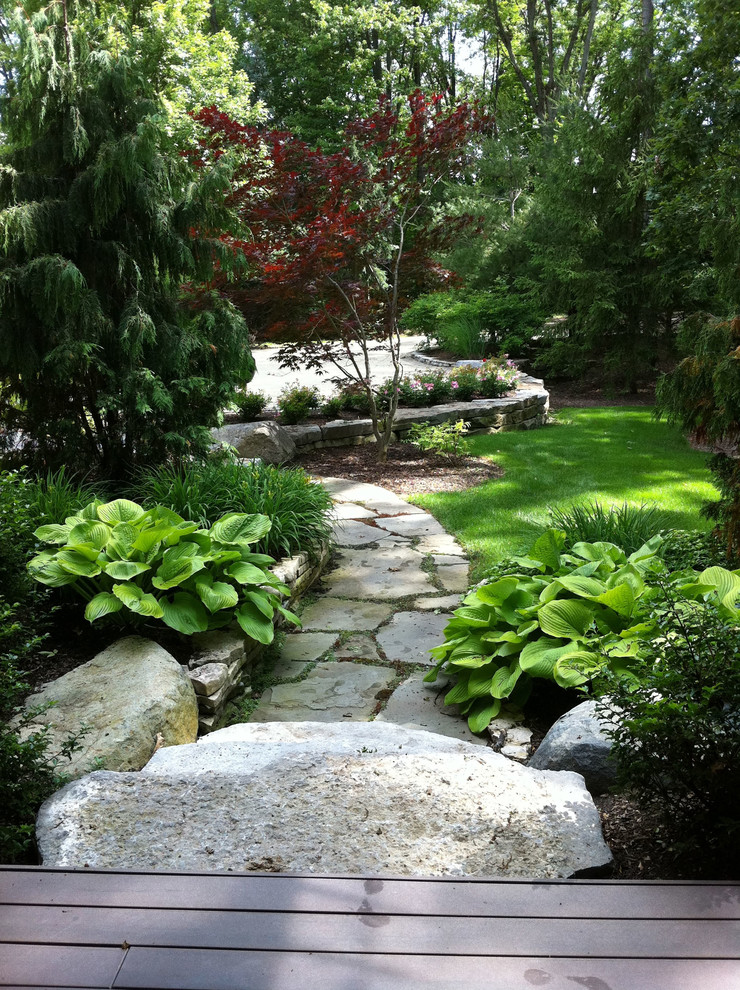 Imagen de jardín tradicional grande en primavera en patio delantero con exposición total al sol y adoquines de piedra natural