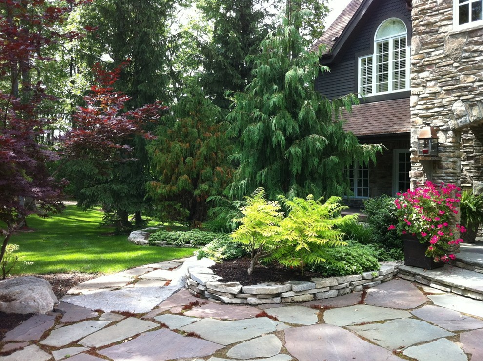 Immagine di un grande giardino tradizionale in ombra davanti casa in primavera con un ingresso o sentiero e pavimentazioni in pietra naturale