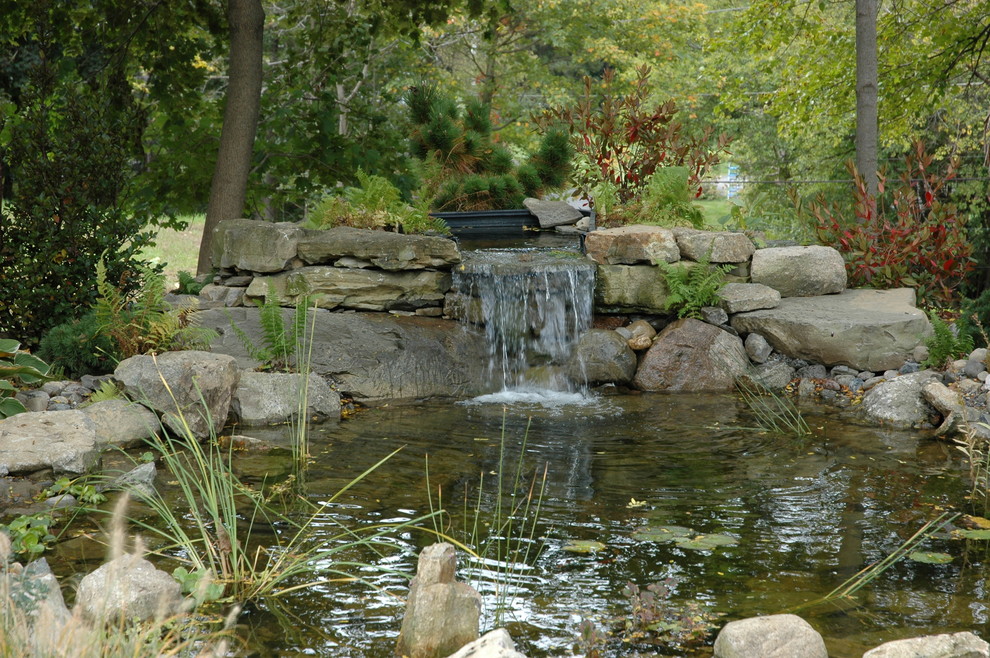 Halbschattiger Klassischer Gartenwasserfall im Frühling, hinter dem Haus mit Natursteinplatten in New York