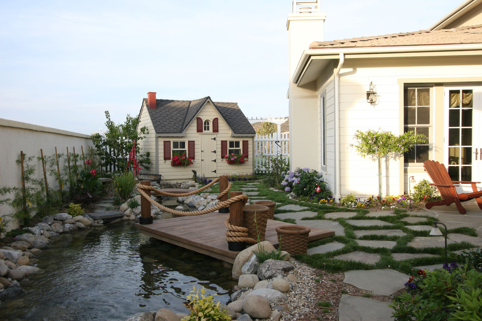 Medium sized traditional back formal partial sun garden in Los Angeles with a water feature and natural stone paving.