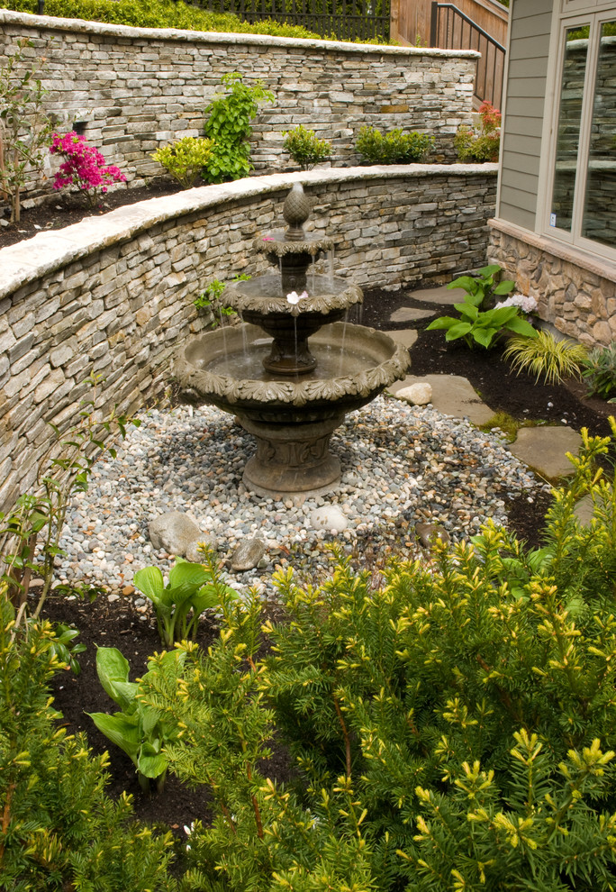 Esempio di un giardino chic con fontane, un pendio, una collina o una riva e ghiaia
