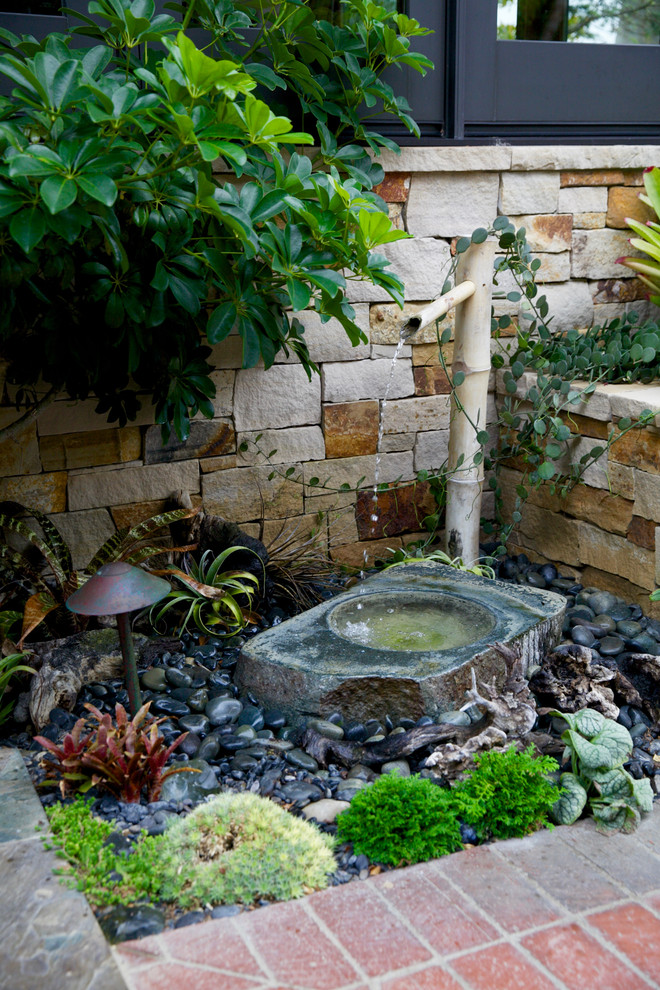 This is an example of a mid-sized tropical side yard brick water fountain landscape in Orange County.