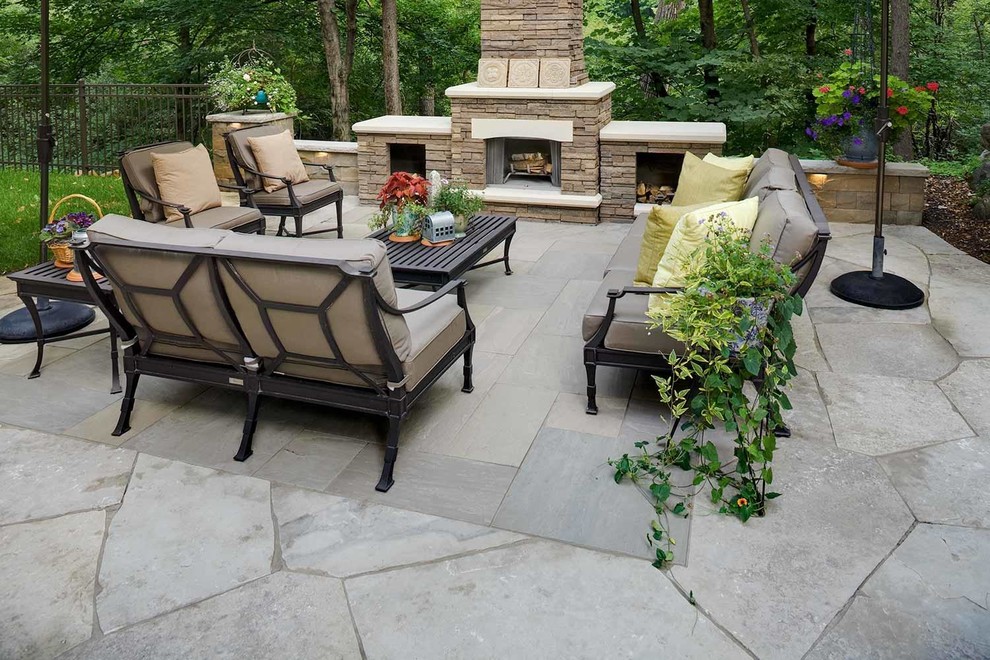Foto de patio clásico renovado grande en patio trasero con chimenea y adoquines de piedra natural