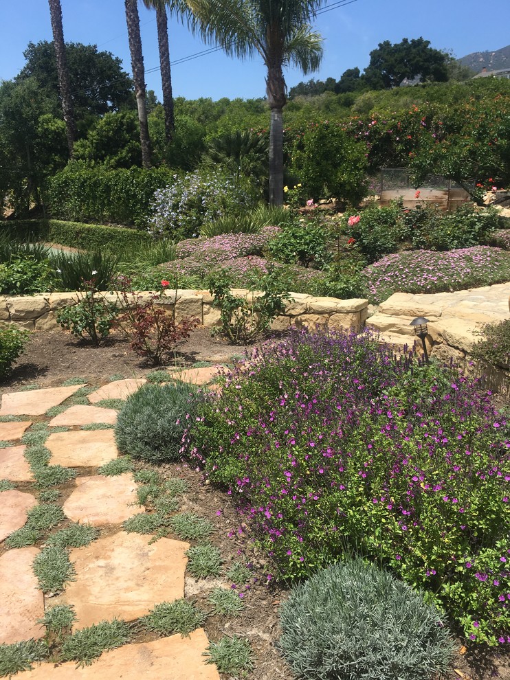 Idee per un giardino mediterraneo dietro casa con un muro di contenimento e pavimentazioni in pietra naturale