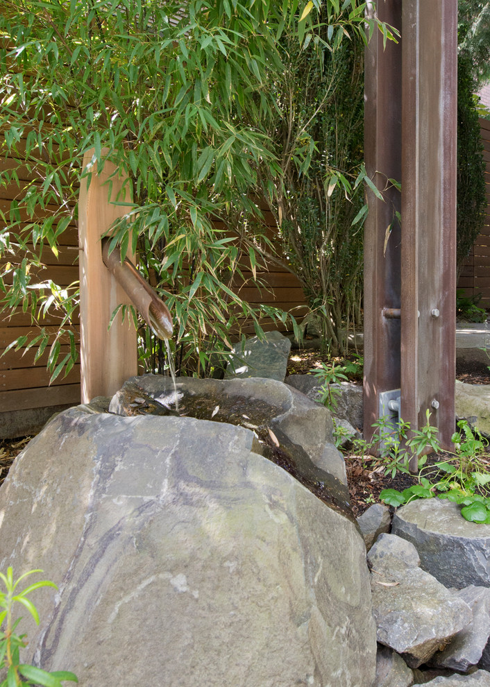 Modern side partial sun garden in Seattle with a water feature and natural stone paving.