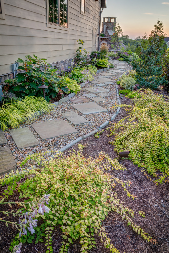 This is an example of a large classic side partial sun garden for summer in Cleveland with a garden path and gravel.