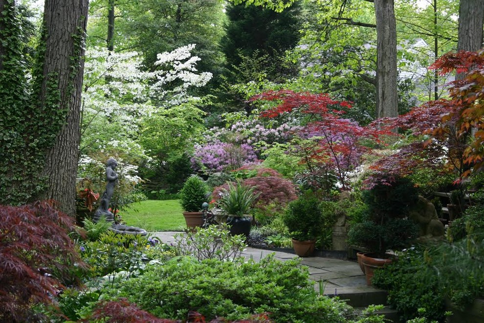 Modelo de jardín clásico de tamaño medio en primavera en patio trasero con exposición parcial al sol y adoquines de piedra natural