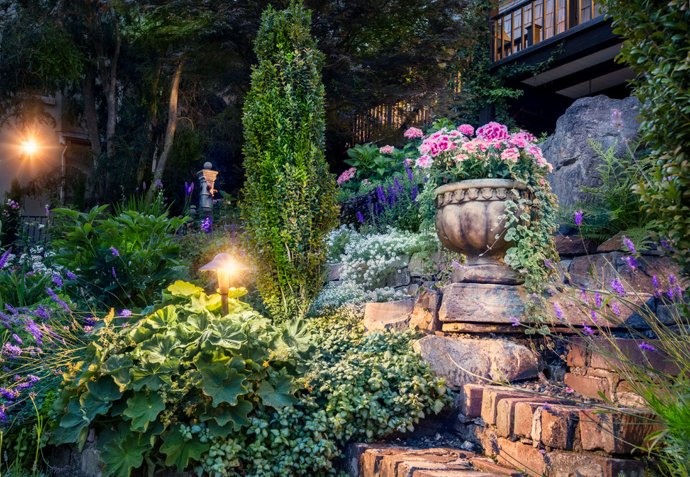 Aménagement d'un grand jardin arrière classique au printemps avec une exposition ensoleillée et des pavés en brique.
