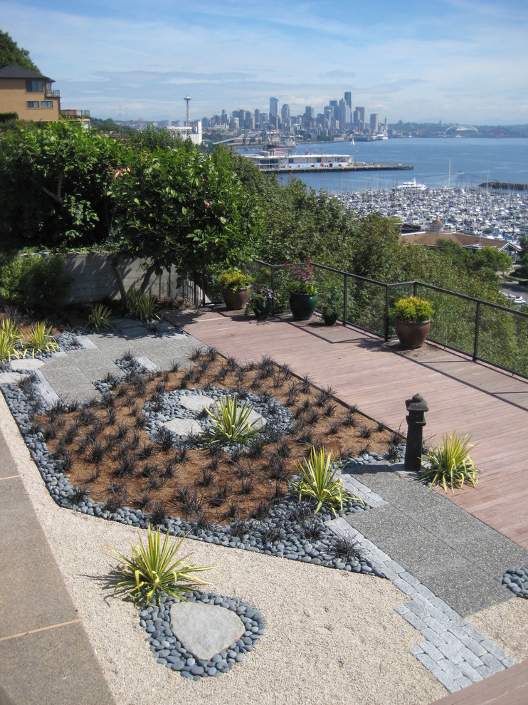 This is an example of a mid-sized modern full sun backyard stone landscaping in Seattle.