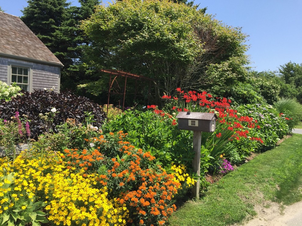 На фото: солнечный, летний регулярный сад среднего размера на переднем дворе в классическом стиле с садовой дорожкой или калиткой, хорошей освещенностью и мульчированием