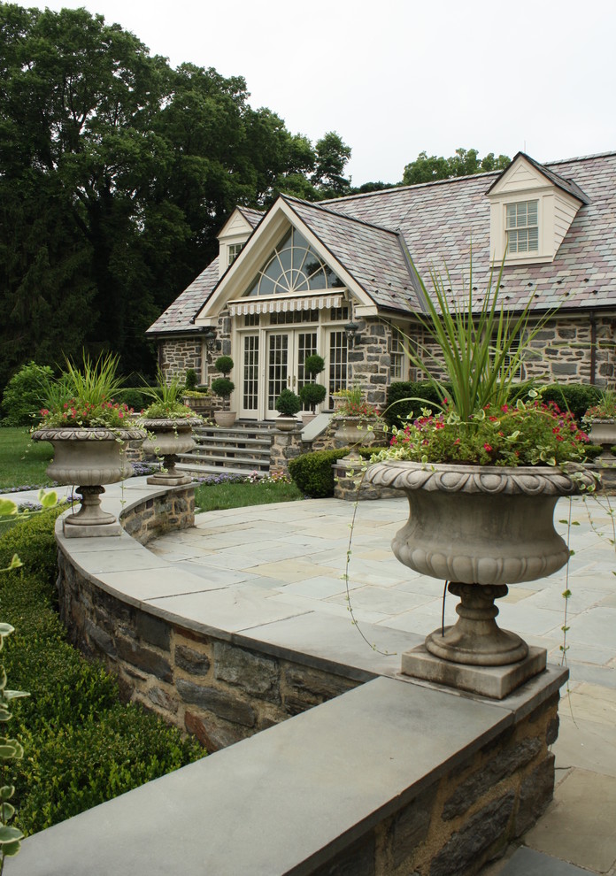 Aménagement d'un grand jardin arrière classique avec une exposition ensoleillée et des pavés en pierre naturelle.