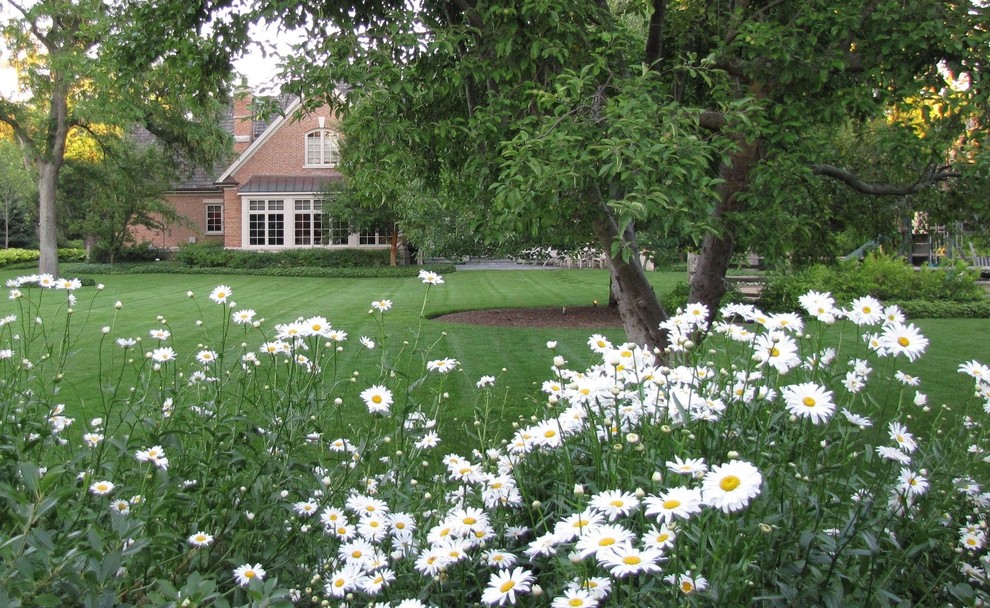 На фото: большой летний участок и сад на заднем дворе в классическом стиле с полуденной тенью с