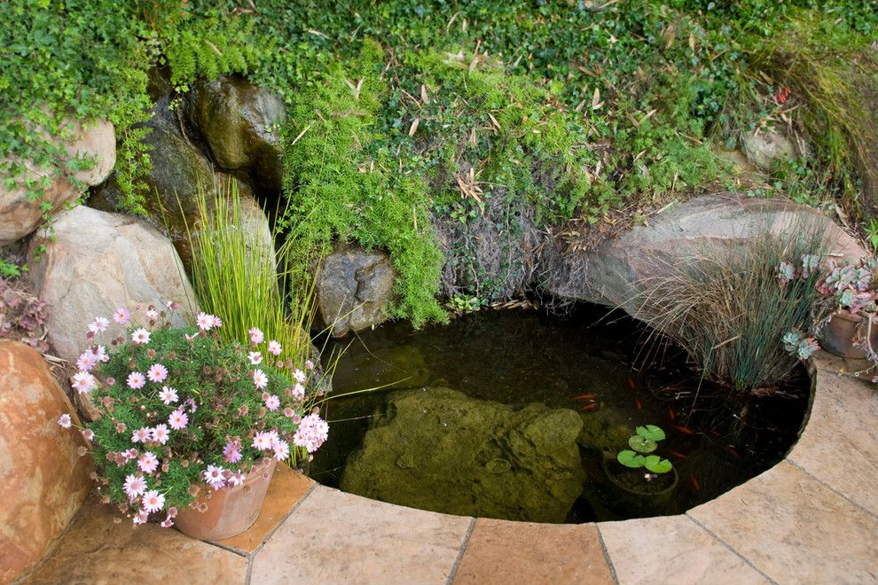 Imagen de jardín mediterráneo en patio trasero con fuente, exposición parcial al sol y adoquines de piedra natural