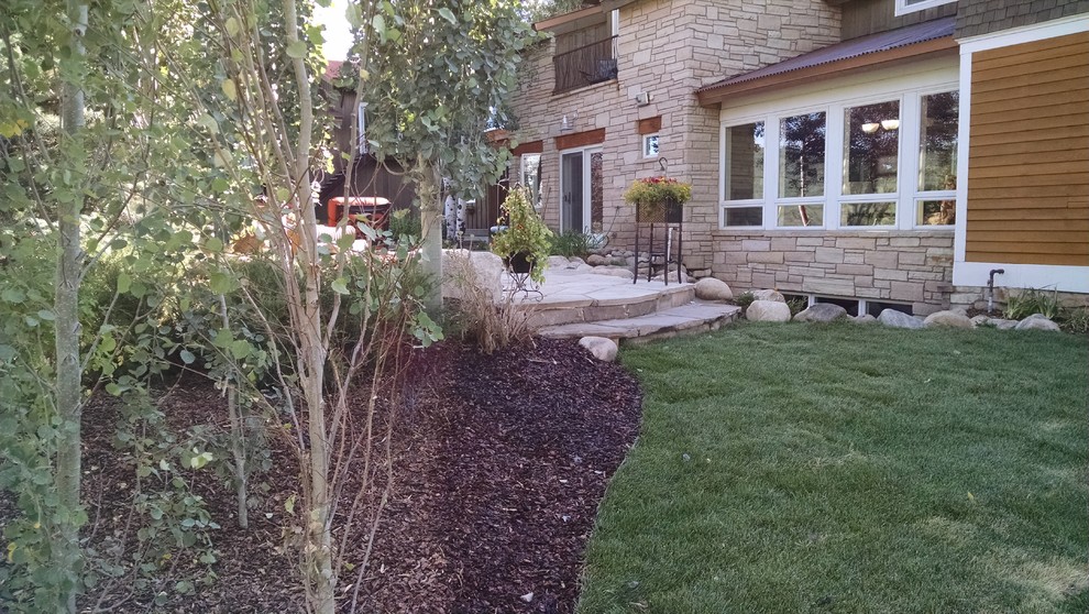 Ejemplo de jardín clásico de tamaño medio en patio trasero con adoquines de piedra natural