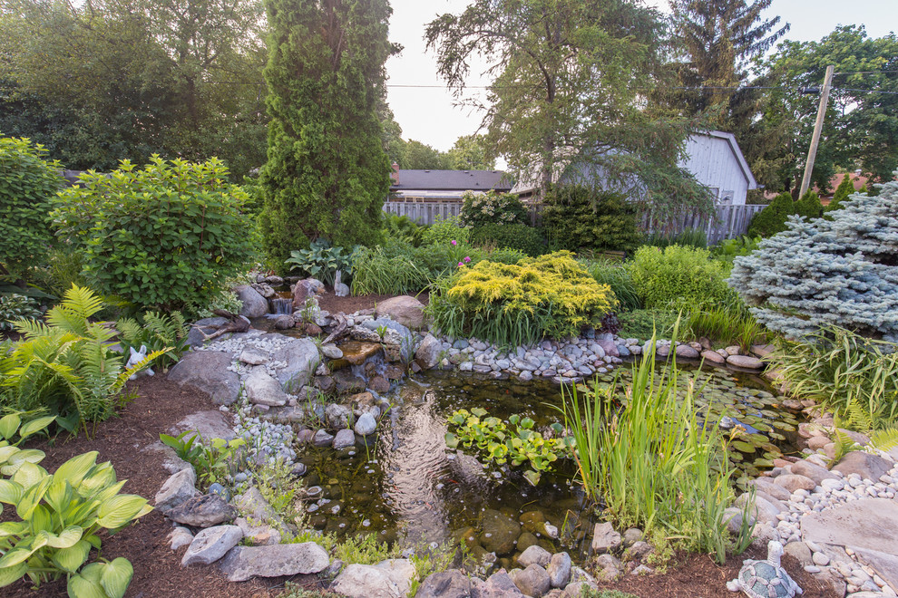 Photo of a mid-sized traditional backyard concrete paver pond in Toronto.