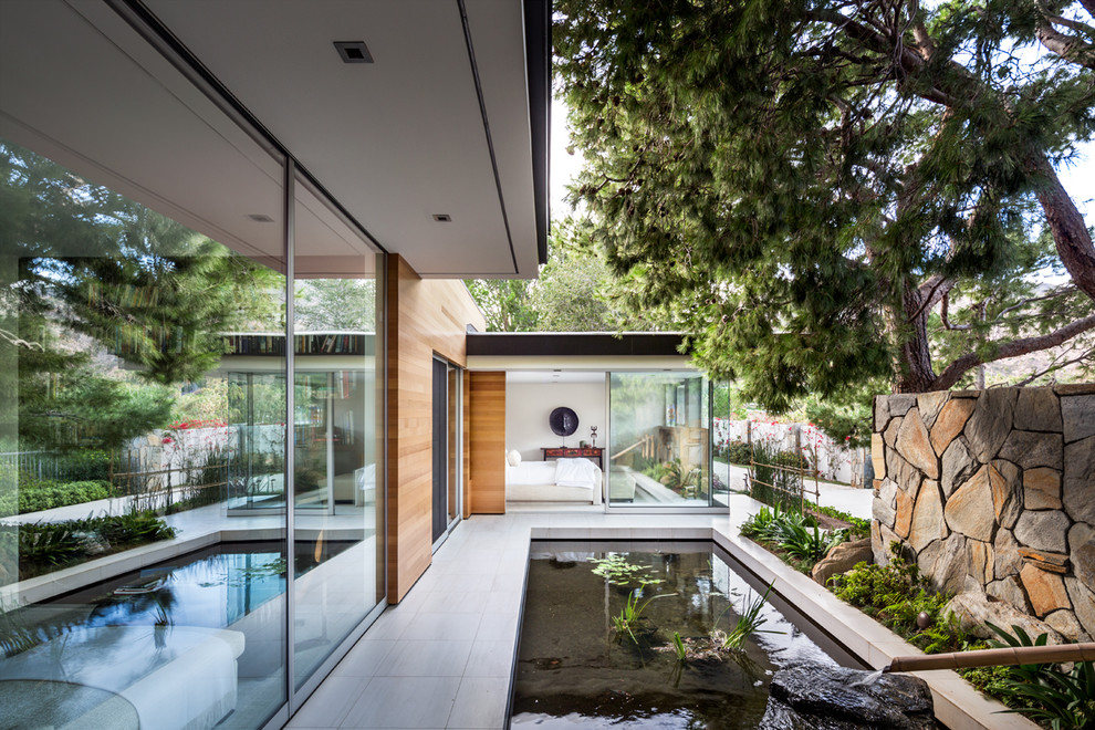 Large midcentury side full sun garden in Los Angeles with a pond and concrete paving.