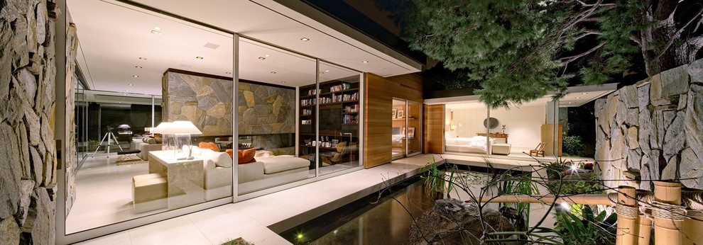 This is an example of a medium sized midcentury side full sun garden in Los Angeles with a pond and concrete paving.