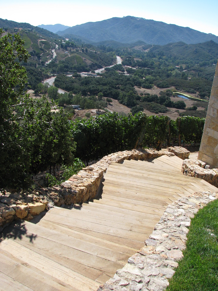 Foto di un ampio giardino mediterraneo esposto in pieno sole in estate con un ingresso o sentiero, ghiaia e un pendio, una collina o una riva