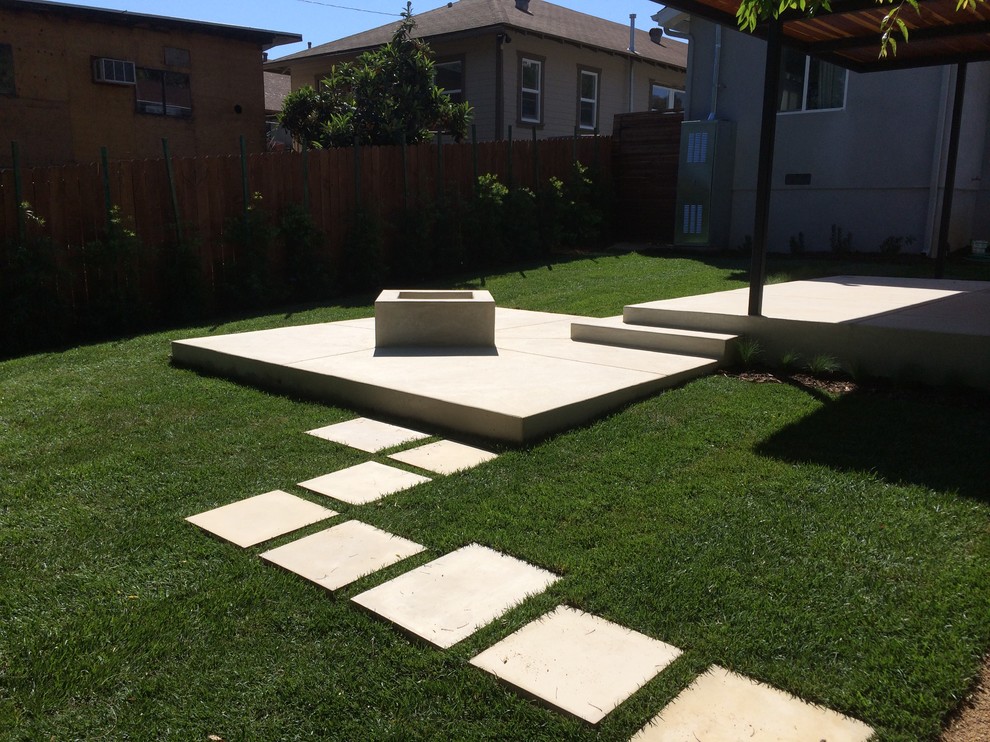 This is an example of a mid-sized modern partial sun backyard concrete paver landscaping in Los Angeles with a fire pit for summer.