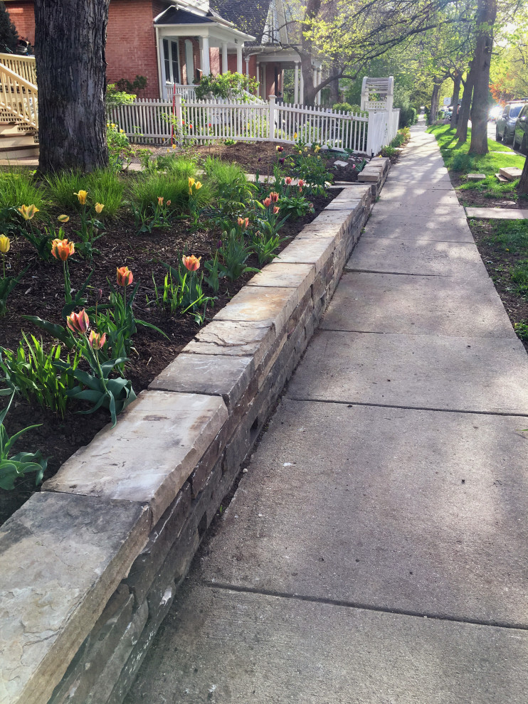 This is an example of a medium sized eclectic front partial sun garden in Denver with a retaining wall.